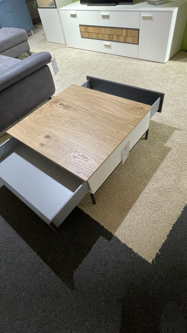 Couchtisch mit einer Holzplatte und zwei offenen Schubladen, auf einem beige-schwarzen Teppich platziert.