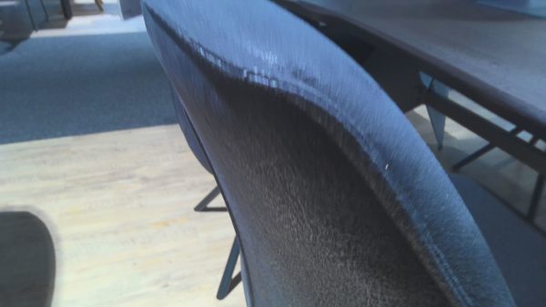 Nahaufnahme der Esstischgruppe Interliving 5116 - ein blauer Stoffstuhl neben einem Holztisch auf einem hellen Holzboden.