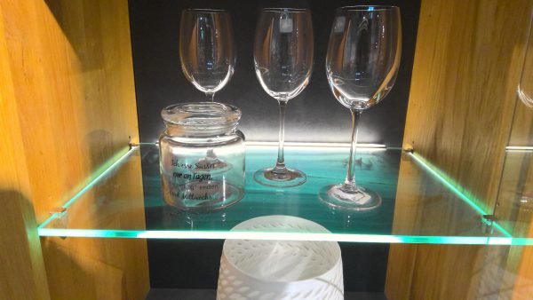 Drei Weingläser und ein Glaskrug werden auf der Vitrine Interliving-5603 mit einem Holzhintergrund ausgestellt.
